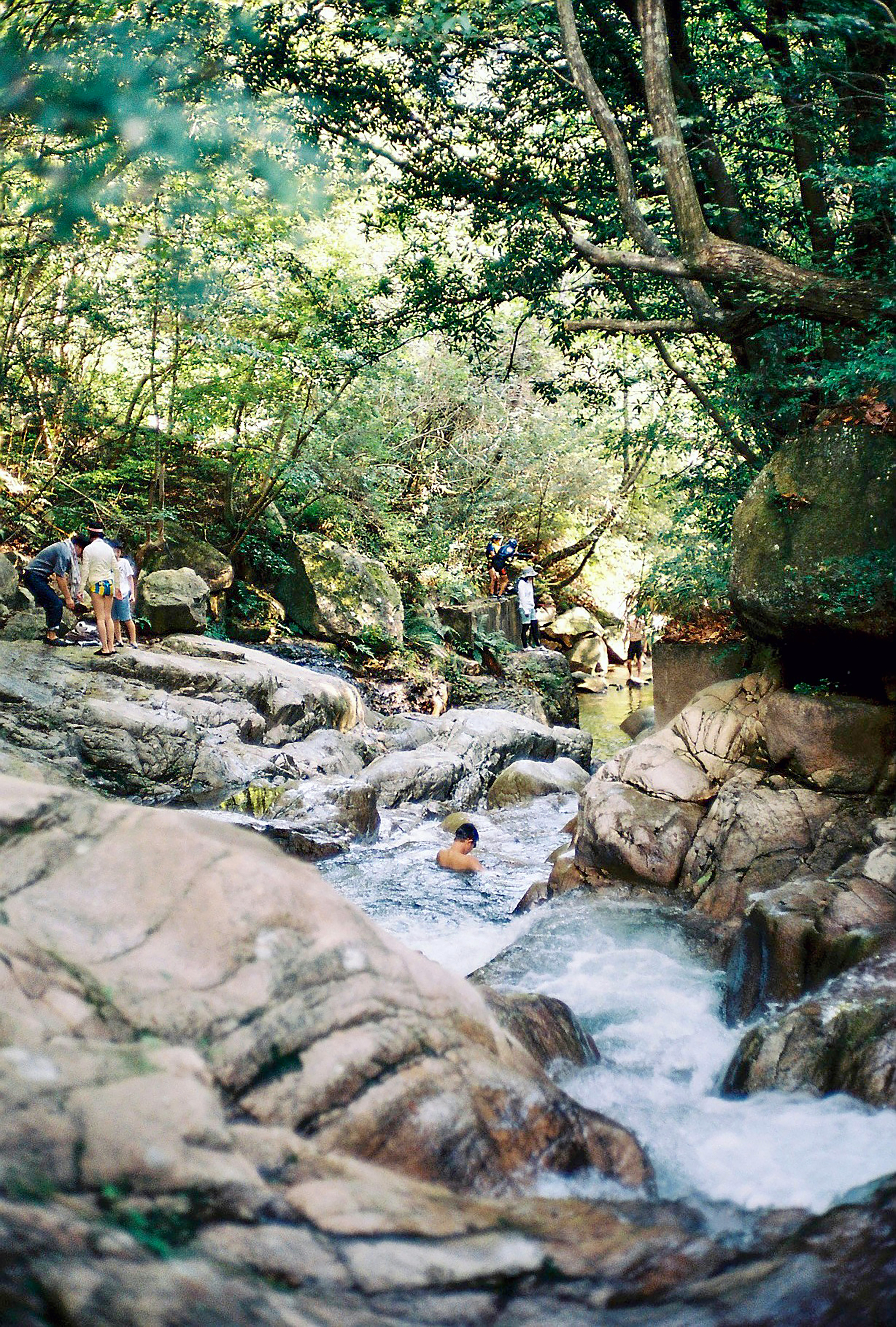 people walking on rocky river during daytime